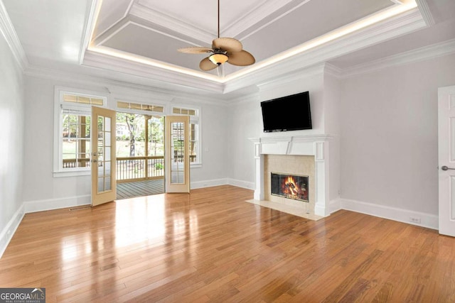 unfurnished living room with ornamental molding, a raised ceiling, a fireplace, light hardwood / wood-style floors, and ceiling fan