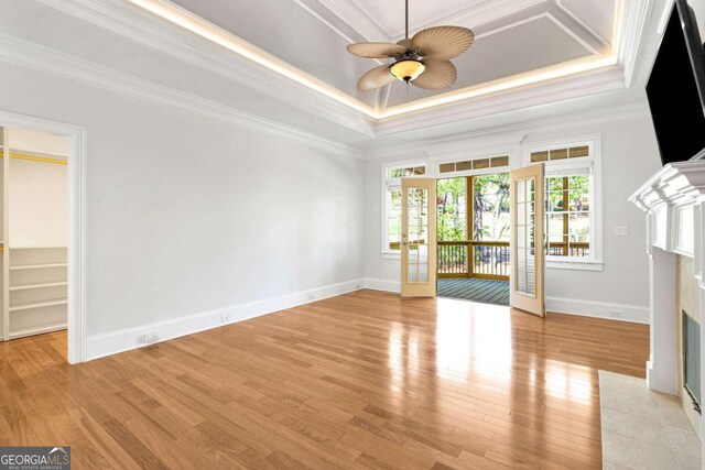 unfurnished living room featuring light hardwood / wood-style flooring, a tray ceiling, and crown molding