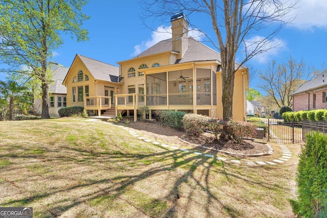 rear view of house with a yard, a deck, and ceiling fan