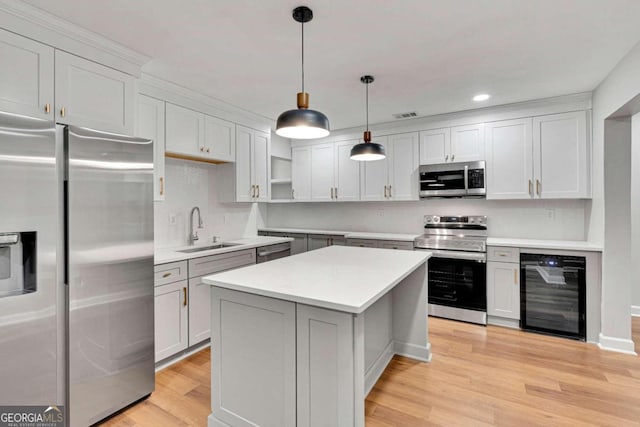 kitchen featuring sink, pendant lighting, beverage cooler, appliances with stainless steel finishes, and light hardwood / wood-style floors