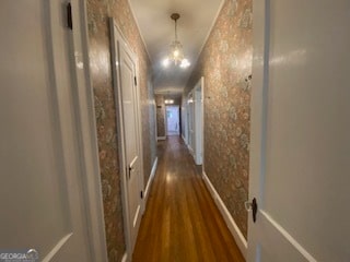 hallway featuring dark wood-type flooring and a notable chandelier