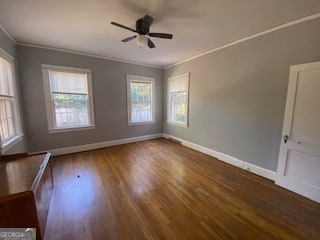 empty room with ornamental molding, ceiling fan, and dark hardwood / wood-style flooring