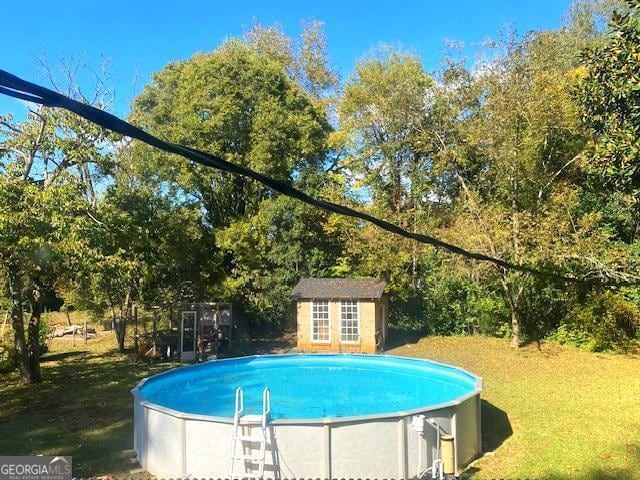 view of pool featuring a yard and an outbuilding