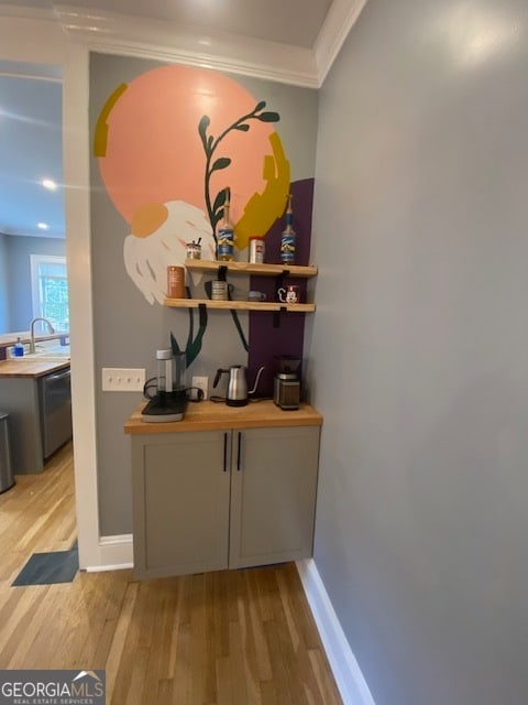 bar featuring light hardwood / wood-style flooring, dishwasher, butcher block counters, and crown molding