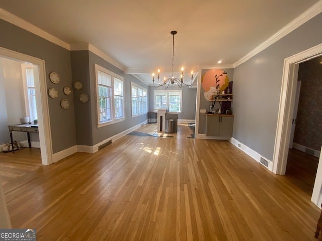 unfurnished dining area featuring hardwood / wood-style flooring, ornamental molding, and a chandelier