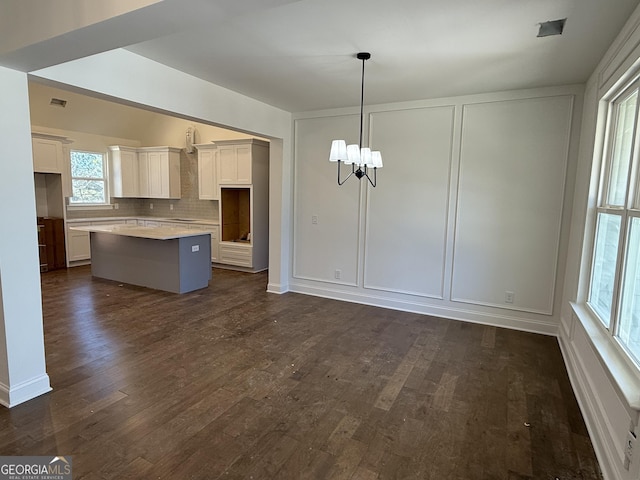 kitchen with an inviting chandelier, decorative light fixtures, dark hardwood / wood-style flooring, a kitchen island, and white cabinets