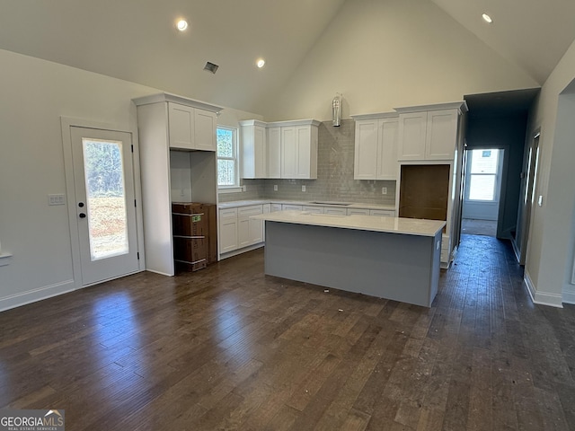 kitchen with white cabinetry, a center island, dark wood-type flooring, and decorative backsplash