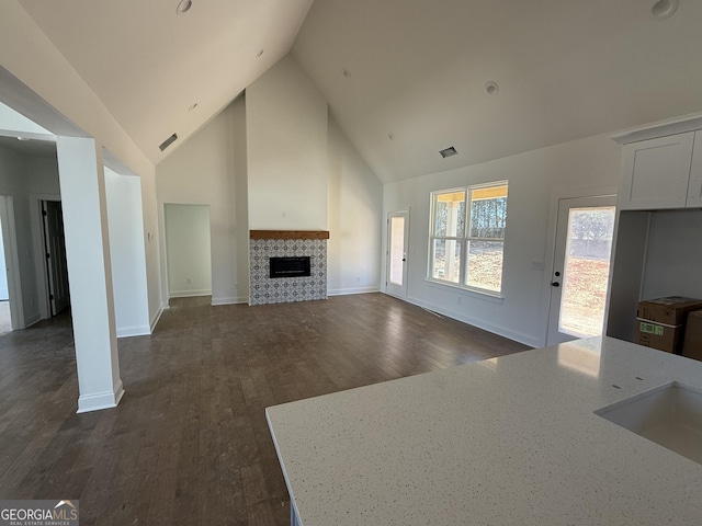 unfurnished living room featuring a fireplace, dark hardwood / wood-style floors, and high vaulted ceiling