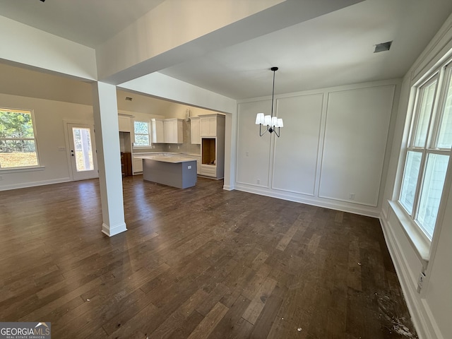 unfurnished living room featuring dark wood-type flooring and a notable chandelier