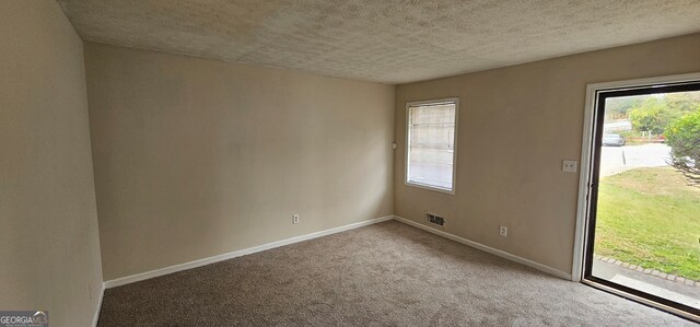 empty room with a textured ceiling and carpet floors