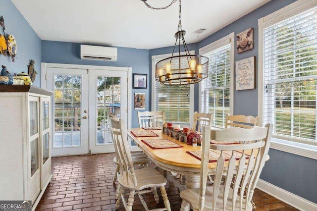 dining space featuring french doors, a wall mounted AC, a chandelier, and plenty of natural light