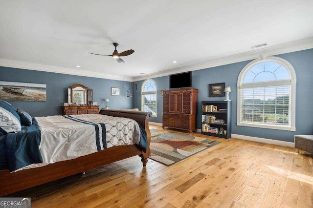 bedroom with multiple windows, crown molding, light wood-type flooring, and ceiling fan