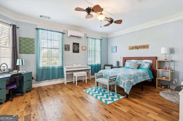 bedroom with an AC wall unit, crown molding, light hardwood / wood-style floors, and ceiling fan