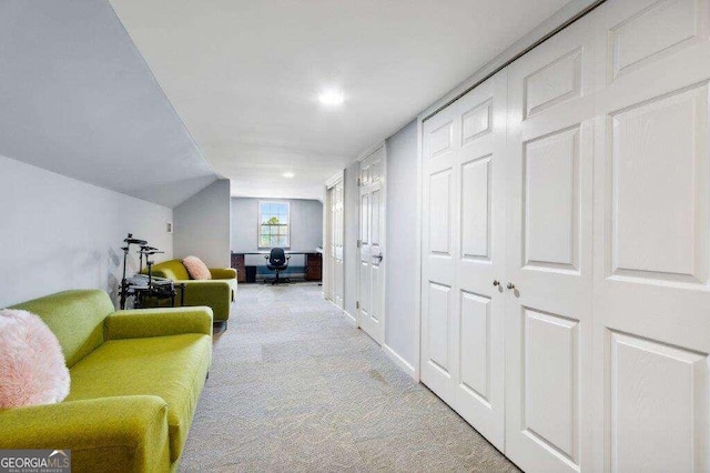 hall featuring lofted ceiling and light colored carpet