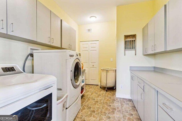 washroom with independent washer and dryer and cabinets