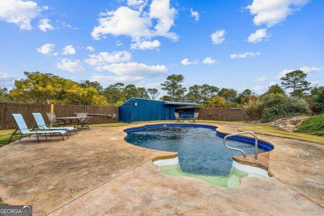 view of pool with a patio area and a shed