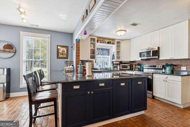 kitchen with appliances with stainless steel finishes, decorative backsplash, white cabinetry, and a center island