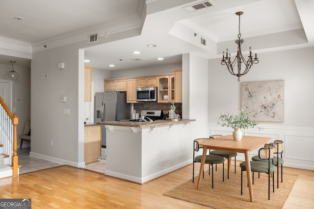 kitchen featuring kitchen peninsula, stainless steel appliances, crown molding, a kitchen bar, and light hardwood / wood-style floors