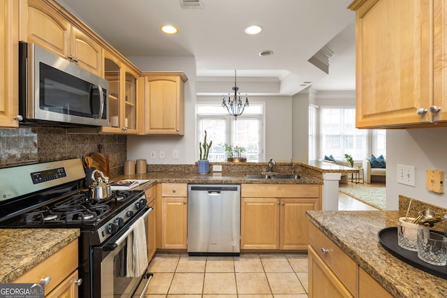 kitchen featuring kitchen peninsula, dark stone counters, sink, light tile patterned flooring, and appliances with stainless steel finishes