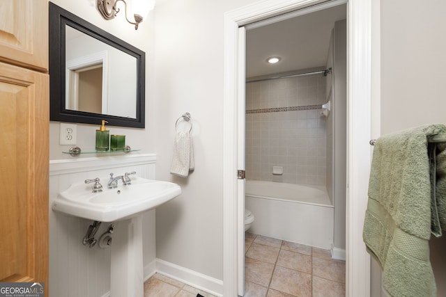 bathroom with tiled shower / bath combo, toilet, and tile patterned flooring