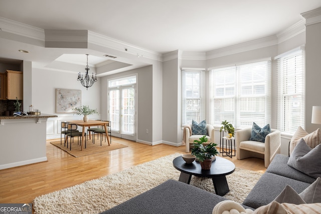 living room with ornamental molding, light hardwood / wood-style flooring, and a chandelier