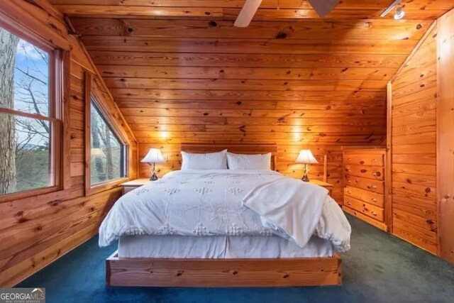 bedroom with vaulted ceiling, dark colored carpet, multiple windows, and wooden ceiling