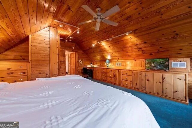 unfurnished bedroom with track lighting, wooden ceiling, carpet, vaulted ceiling, and wood walls