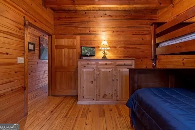 unfurnished bedroom with light hardwood / wood-style floors and wood walls