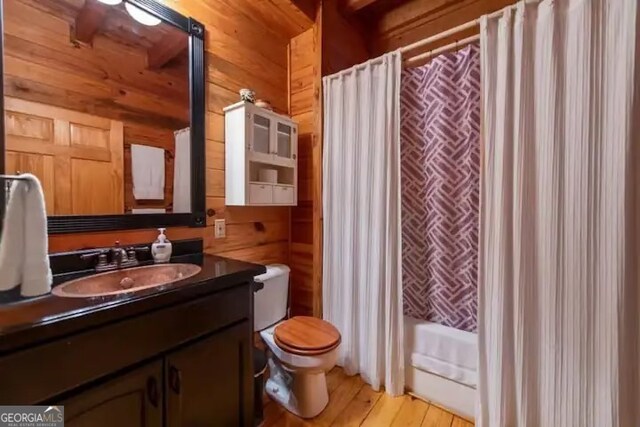 full bathroom with vanity, wood walls, toilet, and wood-type flooring