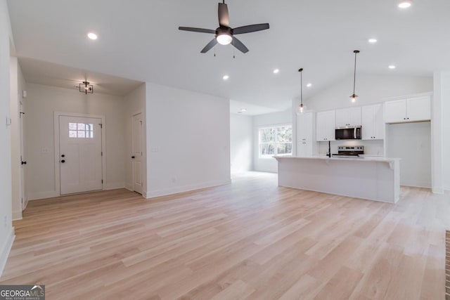 unfurnished living room featuring light hardwood / wood-style floors, ceiling fan, and vaulted ceiling