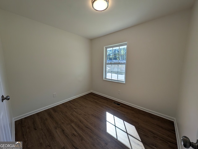 unfurnished room with dark wood-type flooring