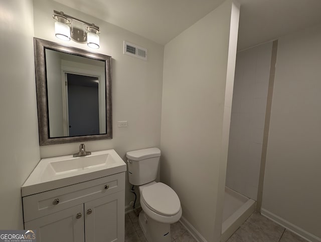 bathroom with a tile shower, tile patterned flooring, vanity, and toilet