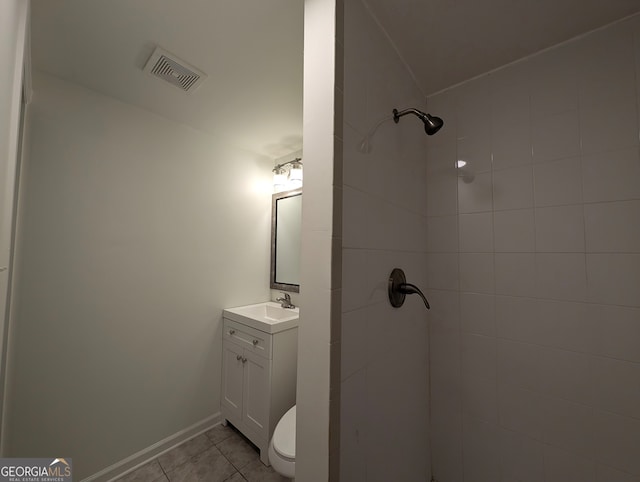 bathroom with tile patterned floors, vanity, a tile shower, and toilet