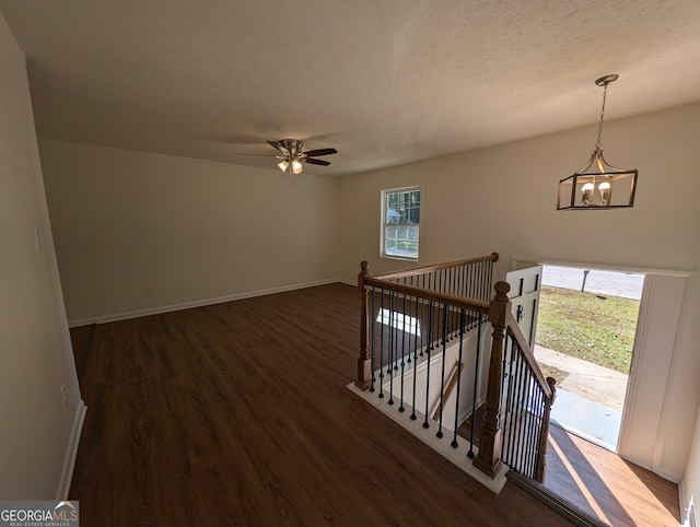 interior space with ceiling fan with notable chandelier, a textured ceiling, and hardwood / wood-style flooring