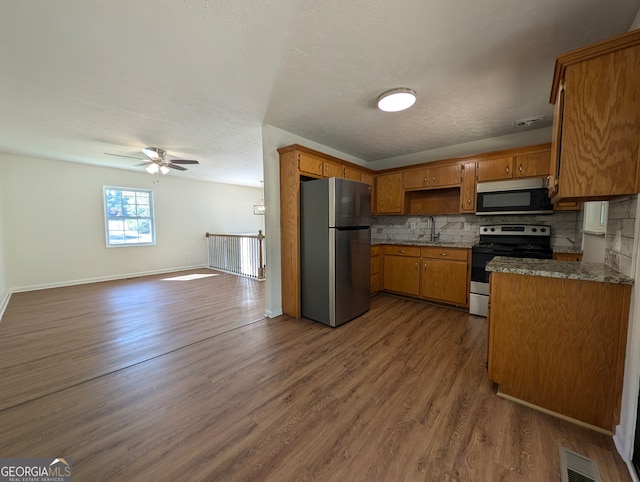 kitchen featuring backsplash, ceiling fan, dark wood-type flooring, and stainless steel appliances