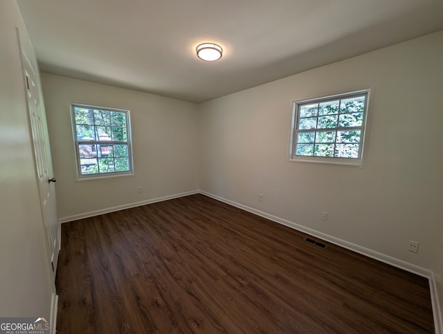 unfurnished room featuring dark hardwood / wood-style flooring and a wealth of natural light