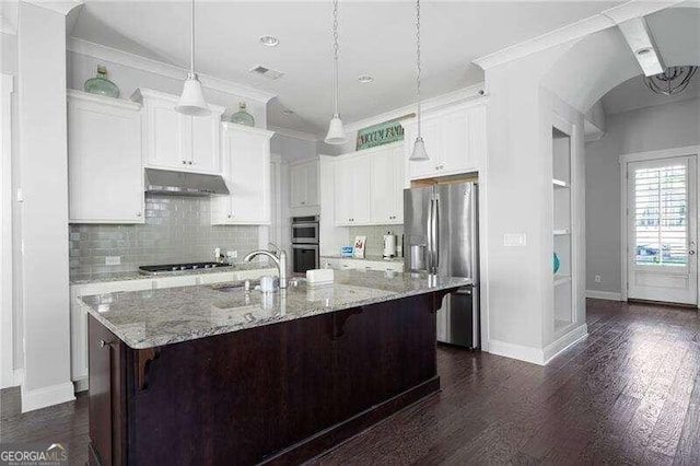 kitchen with light stone countertops, dark hardwood / wood-style flooring, white cabinetry, stainless steel appliances, and a center island with sink