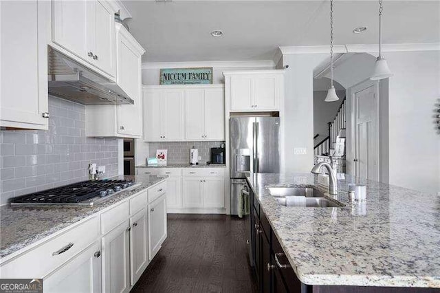 kitchen featuring a center island with sink, appliances with stainless steel finishes, white cabinetry, pendant lighting, and sink