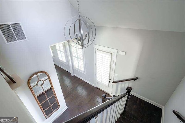 stairway featuring wood-type flooring and an inviting chandelier