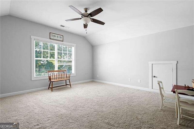 living area with light carpet, ceiling fan, and vaulted ceiling