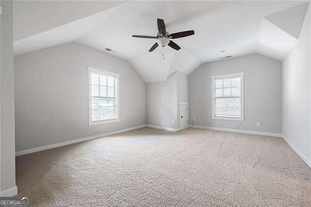 additional living space featuring light carpet, vaulted ceiling, and a wealth of natural light