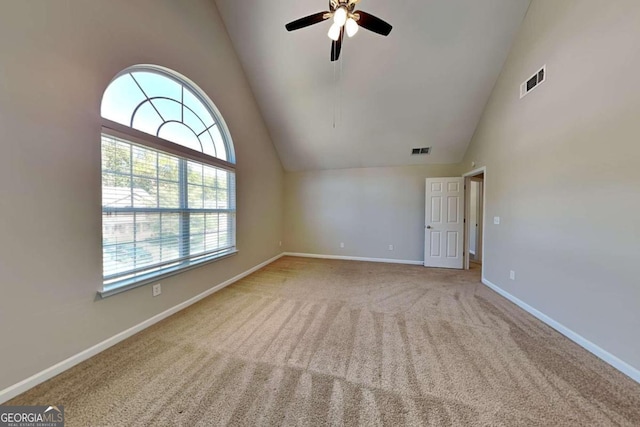 unfurnished room with light carpet, high vaulted ceiling, and plenty of natural light