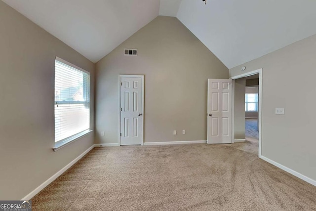 carpeted spare room featuring high vaulted ceiling