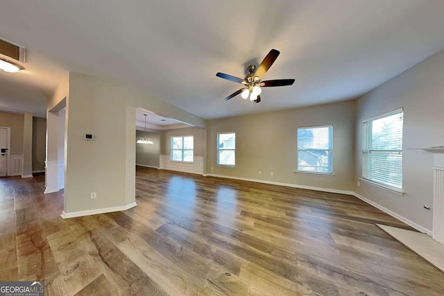 unfurnished room featuring hardwood / wood-style flooring, ceiling fan with notable chandelier, and plenty of natural light