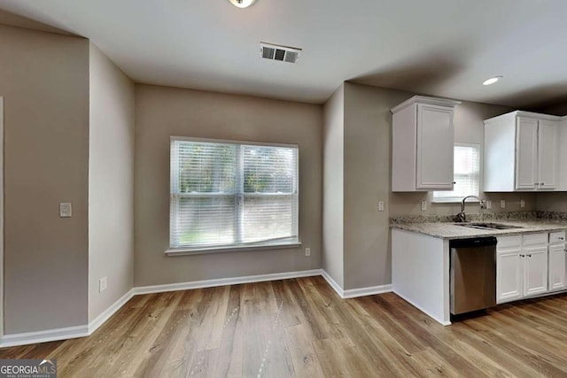 kitchen featuring light stone counters, white cabinetry, stainless steel dishwasher, light hardwood / wood-style floors, and sink