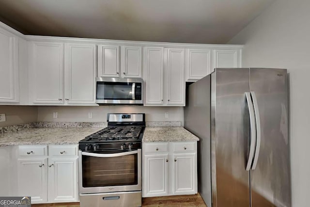 kitchen featuring light stone counters, stainless steel appliances, light hardwood / wood-style flooring, and white cabinets