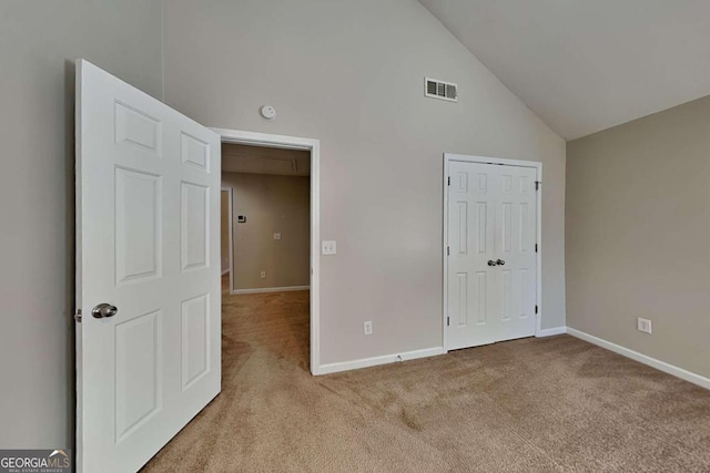 unfurnished bedroom with high vaulted ceiling and light colored carpet