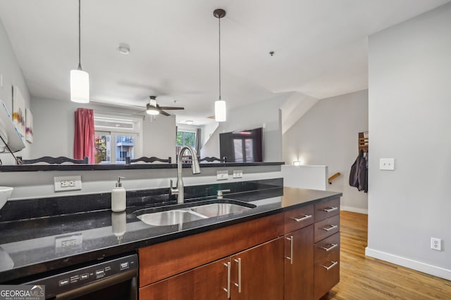 kitchen featuring light hardwood / wood-style flooring, sink, decorative light fixtures, black dishwasher, and dark stone countertops