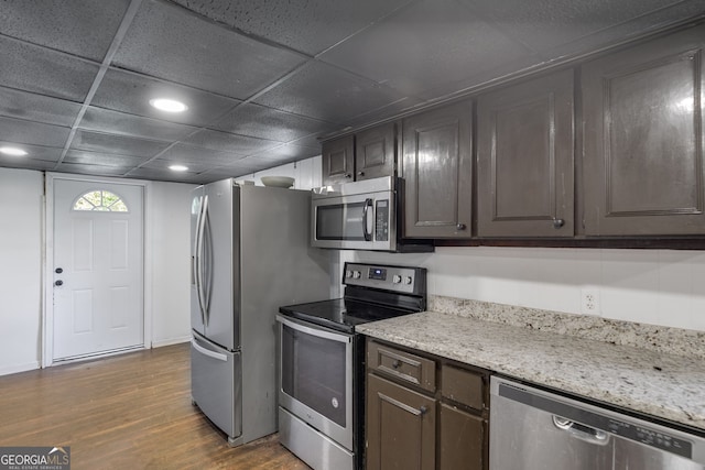 kitchen featuring dark brown cabinets, dark wood-type flooring, stainless steel appliances, and a paneled ceiling