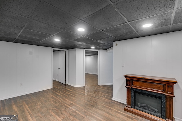 basement with a fireplace, dark hardwood / wood-style floors, and a paneled ceiling